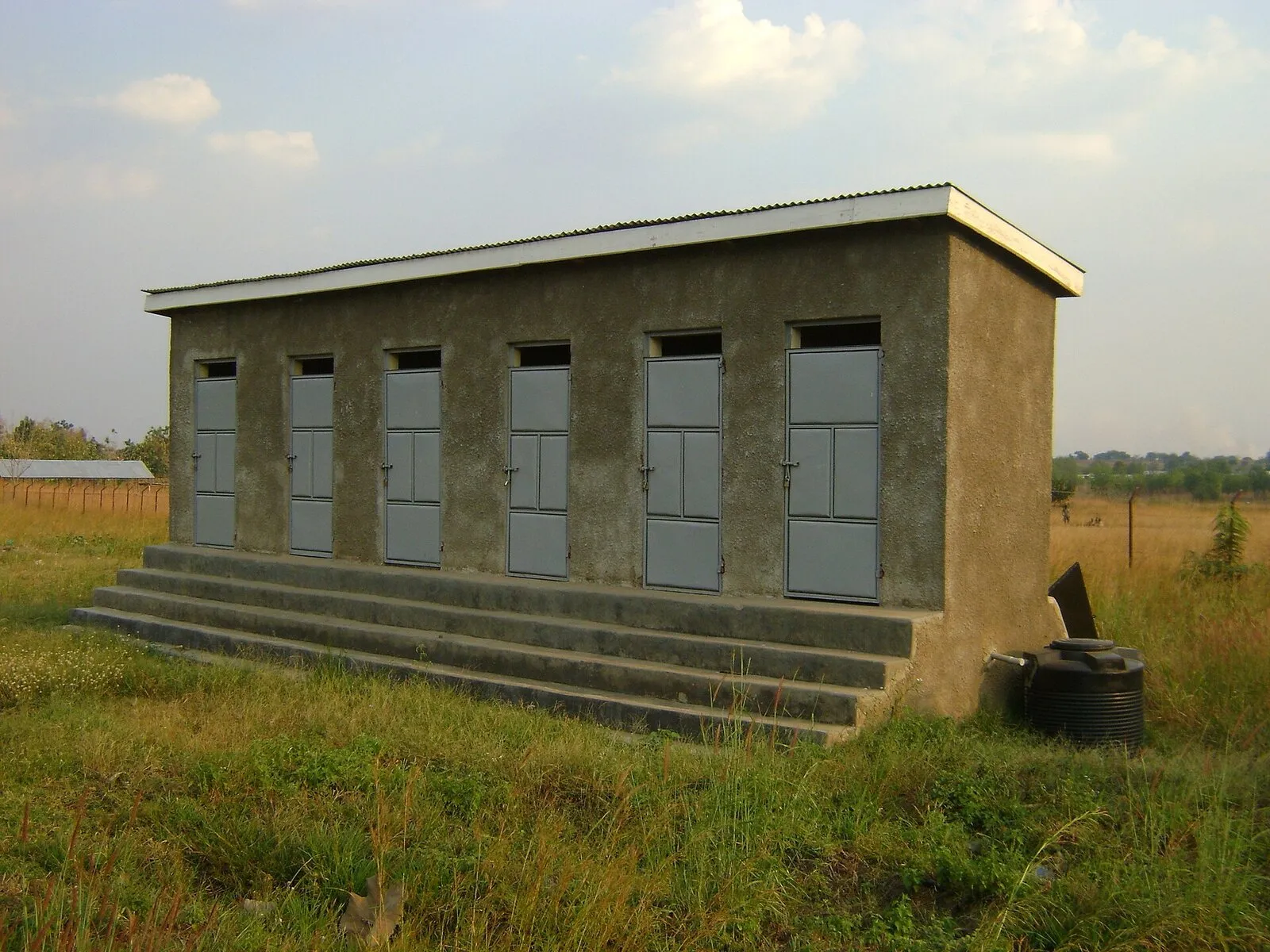 A one-storey concrete school toilet block with several doors